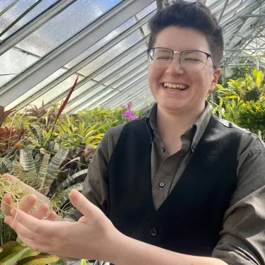 Fish Fisher holds a plant in Lyman, laughing