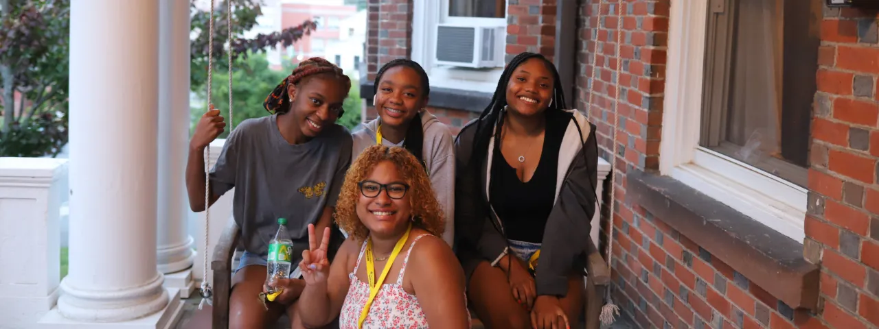 Four Precollege students on the front porch of a Smith house.