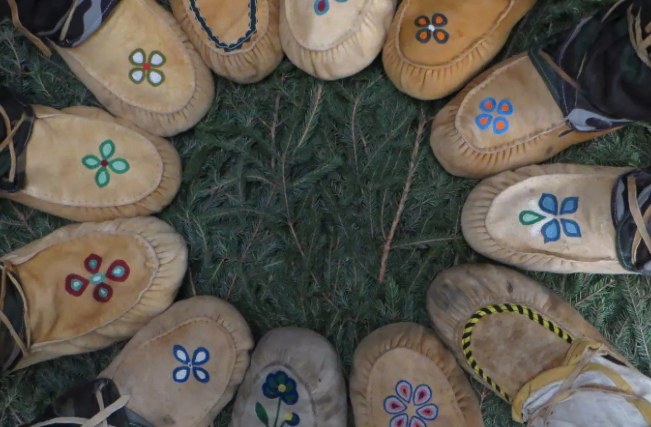 A group of Native Americans standing in a circle wearing moccasins.