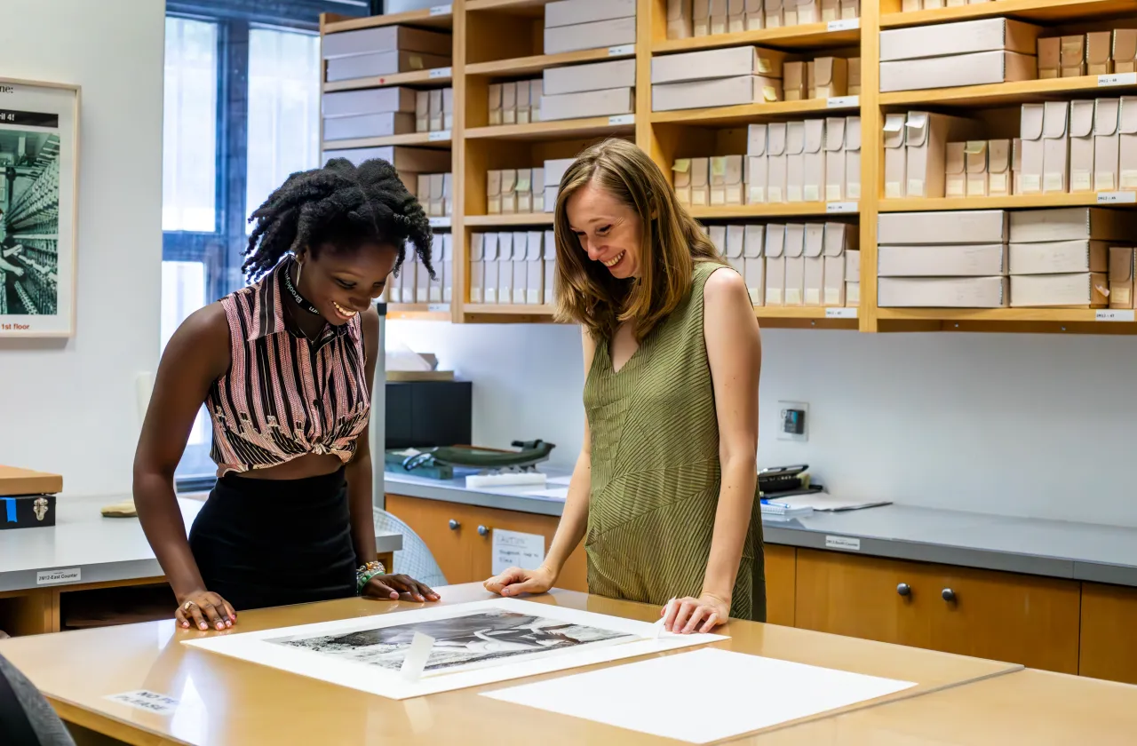 A student and supervisor looking at a photo on a table.