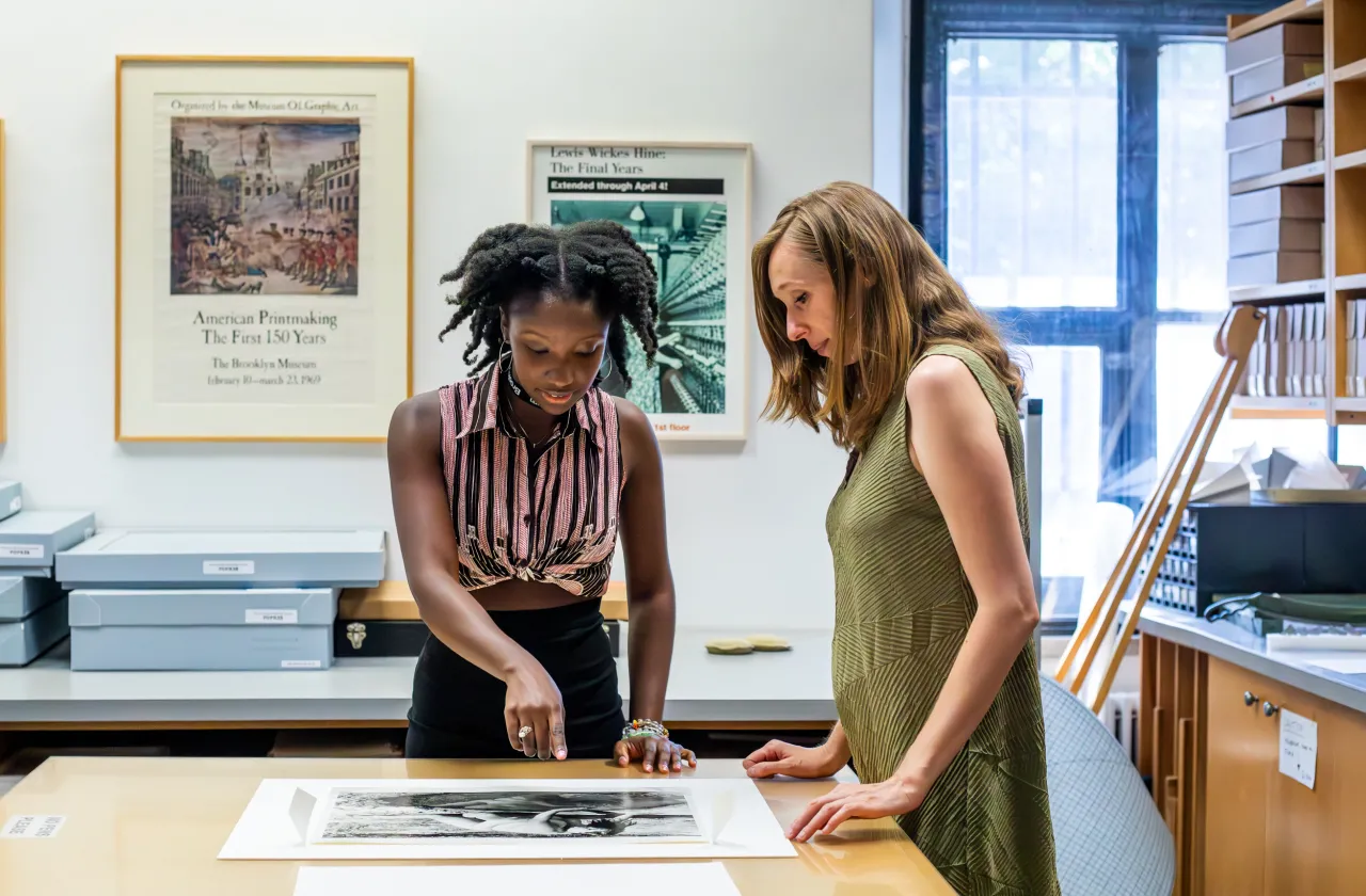 A student and internship supervisor looking at a photo on a table in a museum.