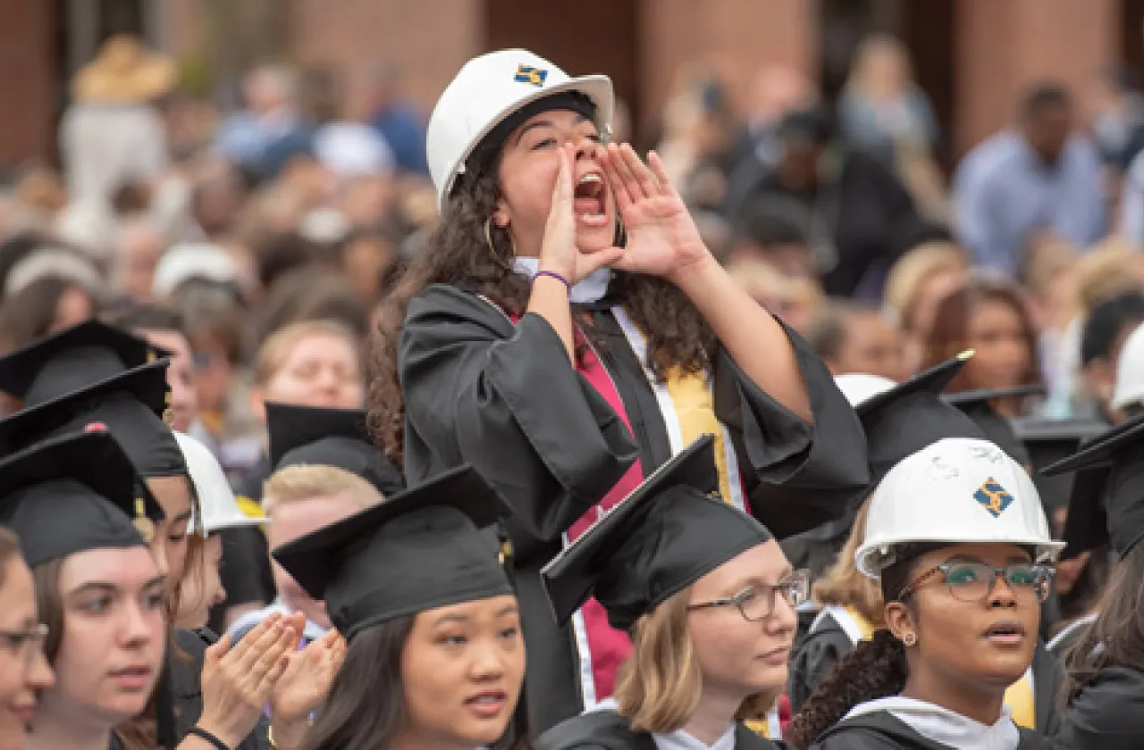 Someone in a graduation hard hat cheering