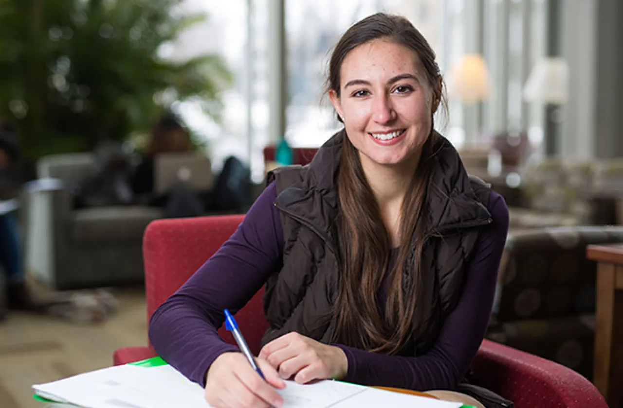 Photo of a smiling student writing in her notebook