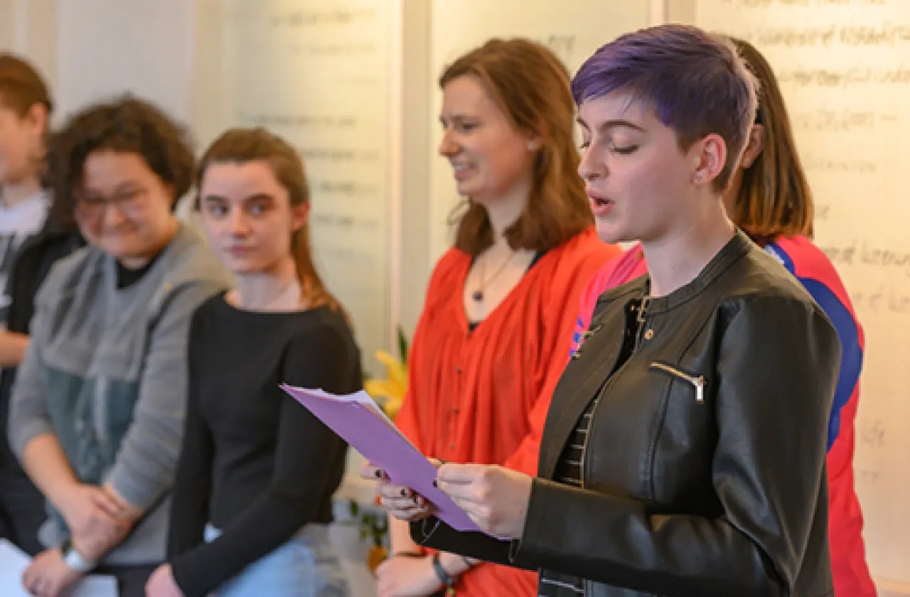 A student reading poetry to a gathered group