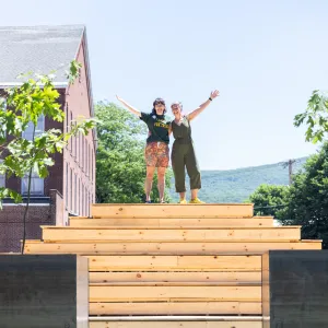 Jess Gersony and Amanda Lovelee stand atop the bleachers in between the two newly planted oak trees.