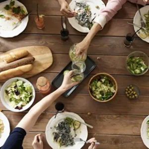 An aerial image of people reaching across a table filled with platters of food.