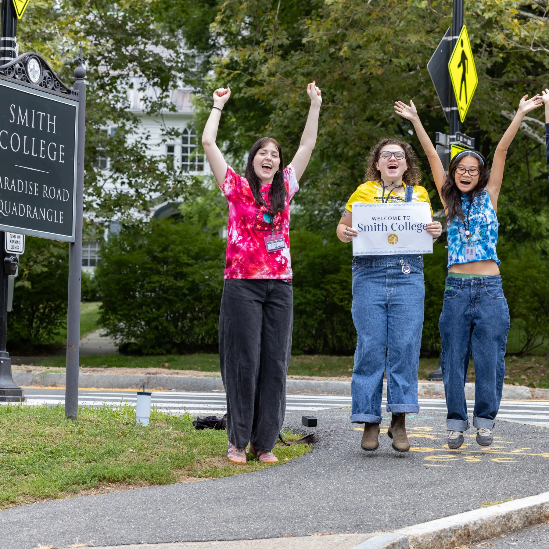 Students jump for joy next to the Quadrangle sign on move-in day 2025