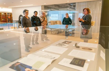 A group of attendees listen to a presentation being given in the library