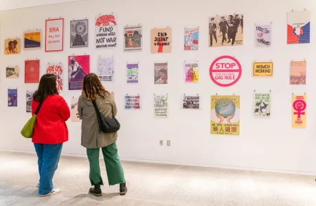 Two attendees talking to each other and admiring political art in a gallery presentation