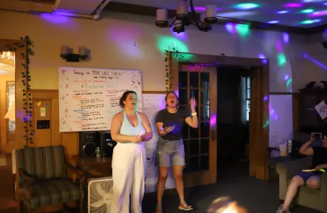 Two students stand in a room with disco lights during an event.