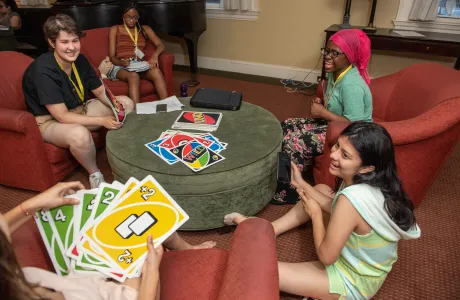 Students sitting in a house living room playing Uno.