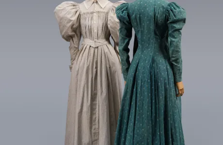 Two floor-length dresses, one grey and one teal, both with large, oversized, puffy long sleeves.