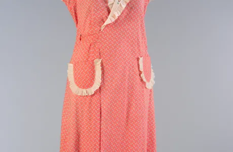 Coral-colored, sleeveless wrap dress with a large lapel and two large pockets on the front.