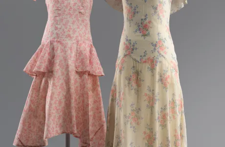 Two dresses, one pink and knee-length, the other cream with pink flowers and floor-length, both with frilly short-sleeves.