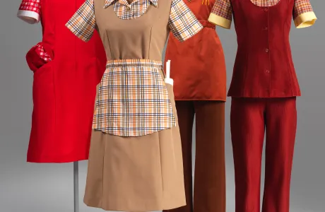Four fast-food uniforms, ranging in color from red to beige, featuring aprons and button-up tops.