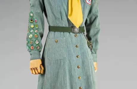 Green long-sleeved, button-up dress with a yellow tie under the color.