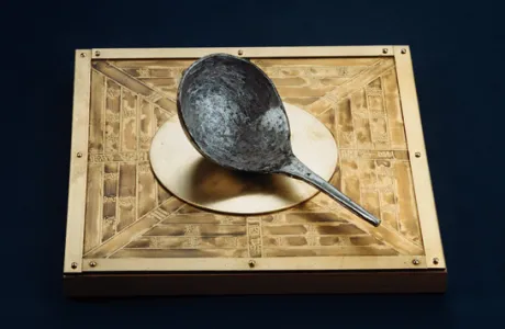 Ancient Chinese compass with a spoon-shaped lodestone on a bronze plate, depicting traditional Chinese symbols