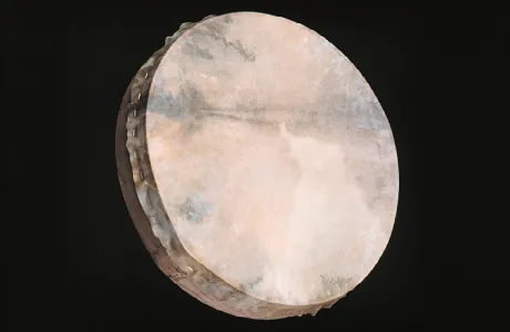 Close-up of a round, handmade drum with a taut, slightly translucent skin, displaying natural textures and subtle earthy tones