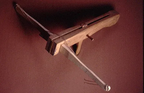 Wooden crossbow with a light wood finish and a taut bowstring