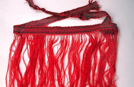 A red and black woven skirt with long, flowing fringes
