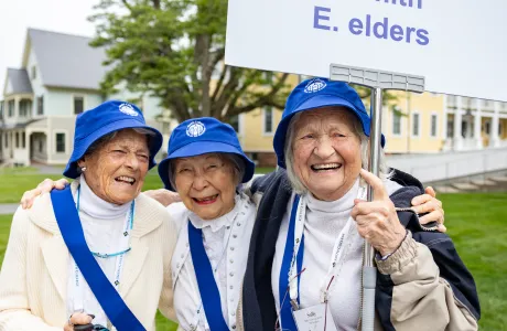 Smithies smile holding a sign that says Wise, Inspired, Smith, Elders