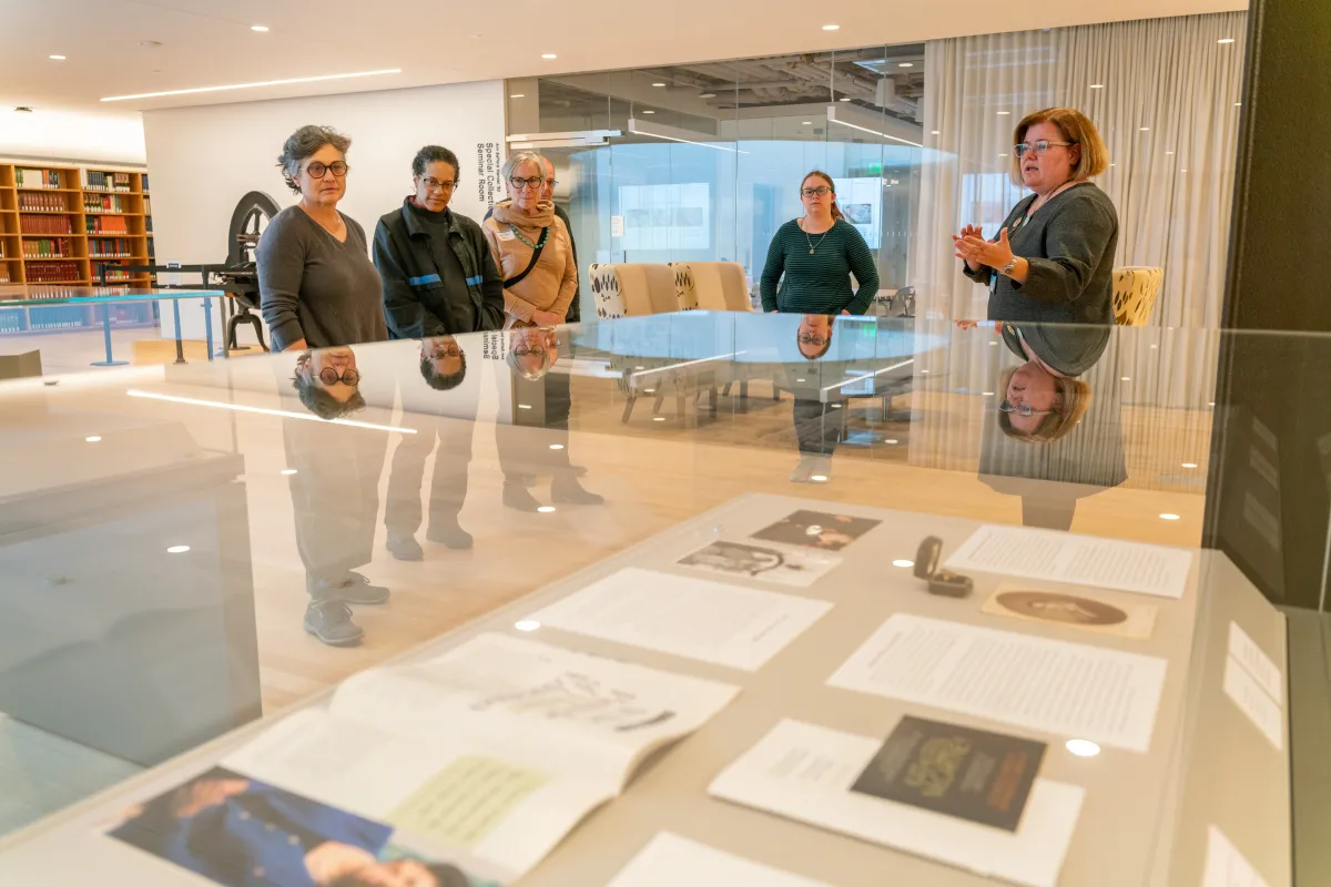 A group of attendees listen to a presentation being given in the library