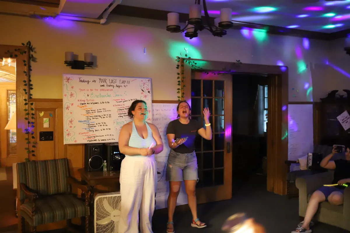 Two students stand in a room with disco lights during an event.