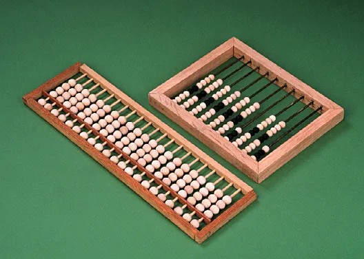 Two wooden abacuses. The left one is laid horizontally with white beads, while the right one is square-shaped with columns of white and black beads.