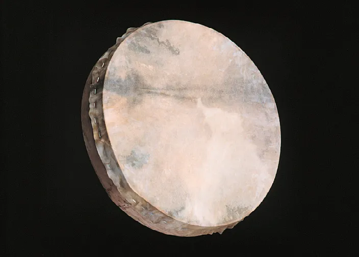Close-up of a round, handmade drum with a taut, slightly translucent skin, displaying natural textures and subtle earthy tones