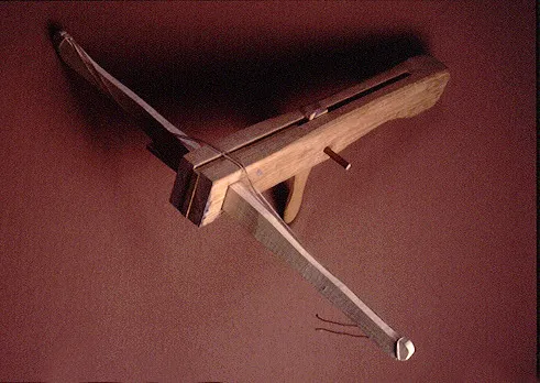 Wooden crossbow with a light wood finish and a taut bowstring