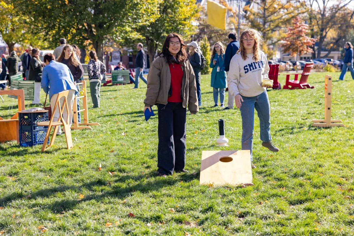 Two people play cornhole during Family Weekend. One is wearing a Smith College sweatshirt.