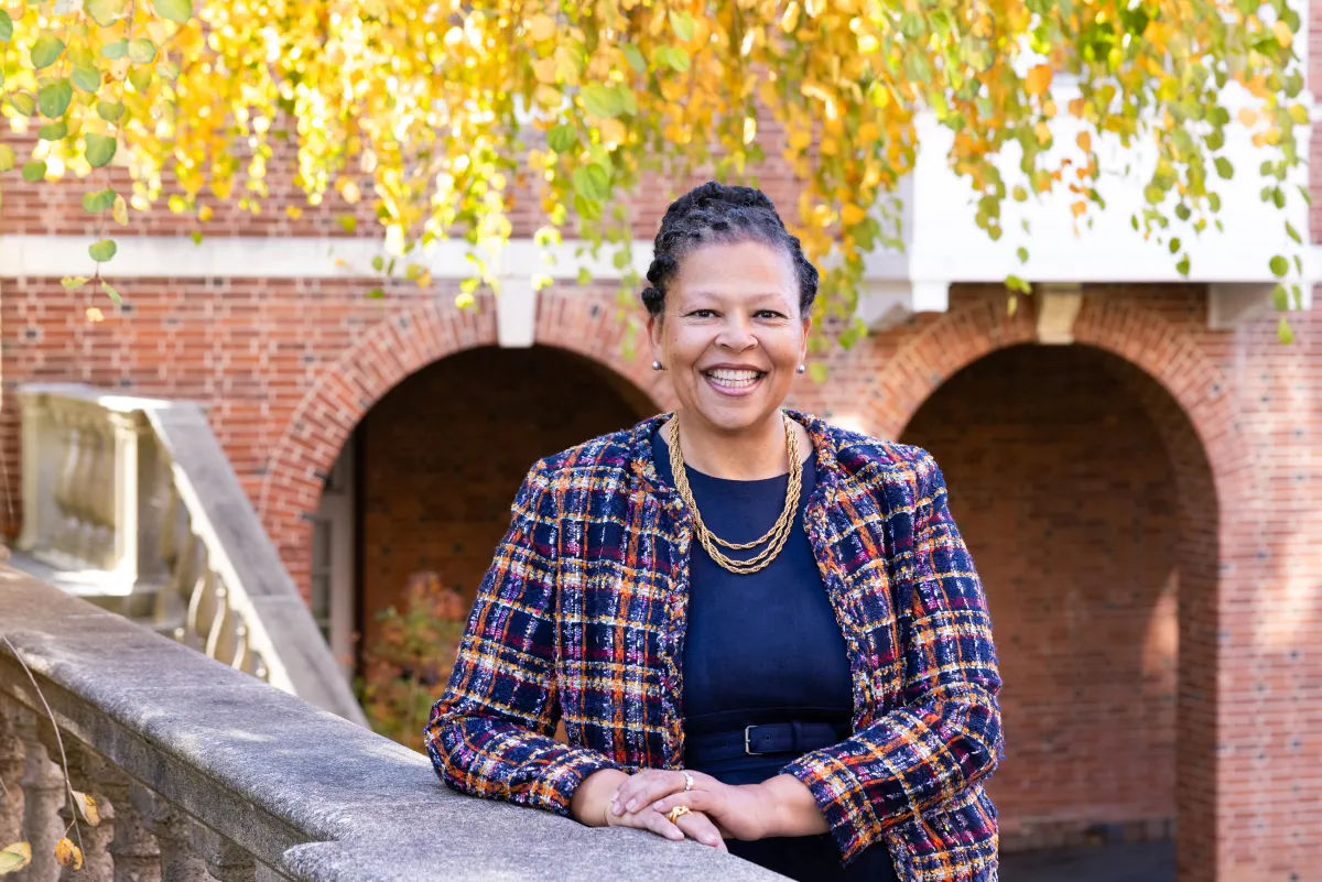 Sarah Willie-LeBreton leaning on a stone banister in the quad at Smith College