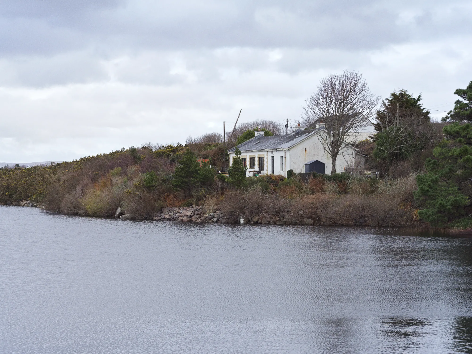 An old white building sits at the edge of a lake in Ireland