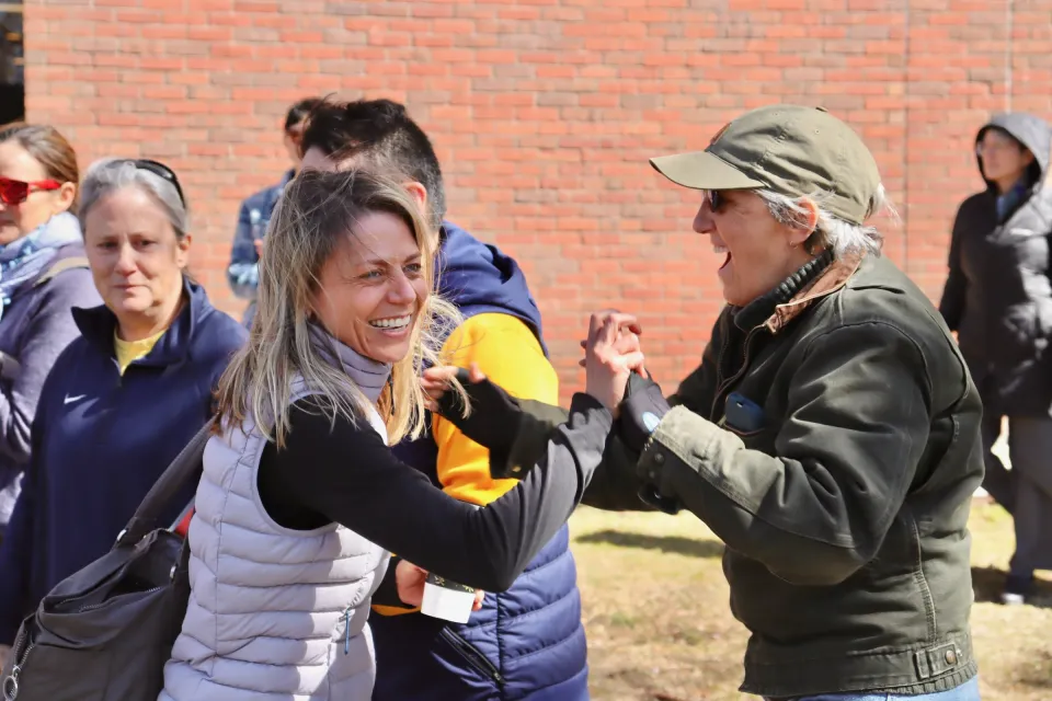 Coach Lynn Hersey smiling and grasping hands with an enthusiastic supporter in attendance.