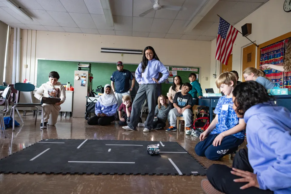 A Smith student looks on as schoolchildren battle with Lego robotics.