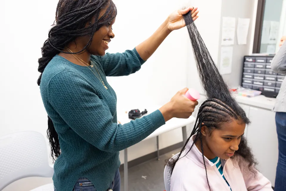 Student researcher Kris Cheaye braiding Gloriamar Esteves’s hair in the MIND lab