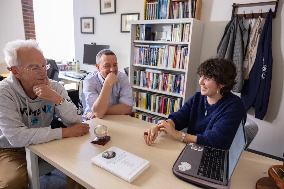 Gabriela Eastwood '26 sits at a computer along with Professors Ben Baumer and Andrew Zimbalist to review their research project