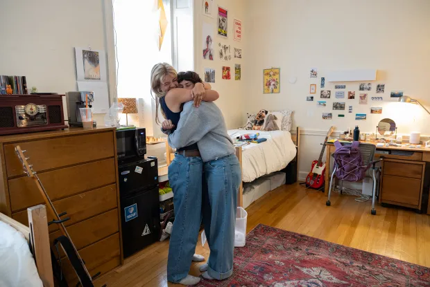 Two students hug in a newly decorated dorm room